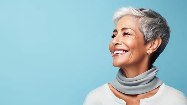 Elegant, smiling elderly, chic latino, Spain woman with gray hair and perfect skin, blue background banner. Advertising of cosmetic products, spa treatments, shampoos and hair care products, dentistry and medicine, perfumes and cosmetology for women