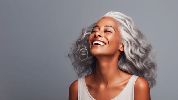 Elegant, elderly, chic latino, Spain woman with gray long hair and perfect skin, gray background, banner. Advertising of cosmetic products, spa treatments, shampoos and hair care products, dentistry and medicine, perfumes and cosmetology for women