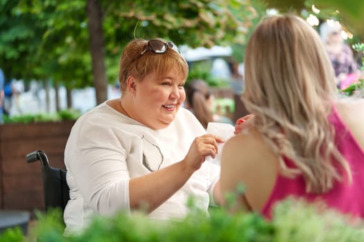 Woman wheelchair user dining at a restaurant with her young daughter, close up