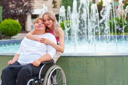 Young daughter taking care of her mother with disability sitting in wheelchair, portrait