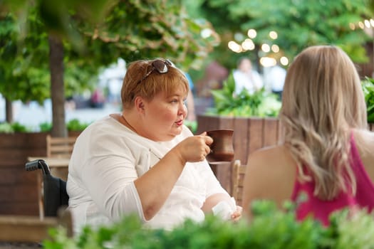 Woman wheelchair user dining at a restaurant with her young daughter, close up