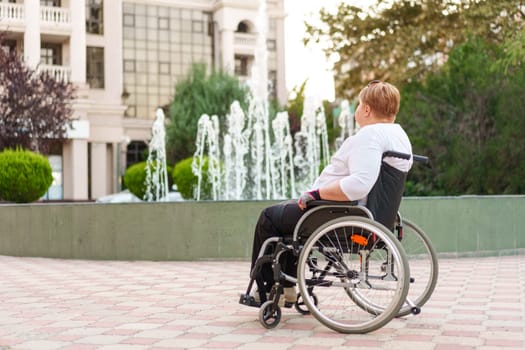 Mature woman sitting in wheelchair outdoors in city