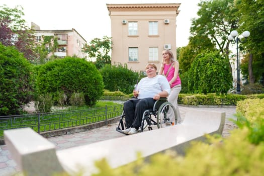 Young woman helping mature woman in wheelchair in the city street