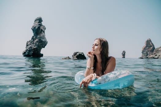 Woman summer sea. Happy woman swimming with inflatable donut on the beach in summer sunny day, surrounded by volcanic mountains. Summer vacation concept