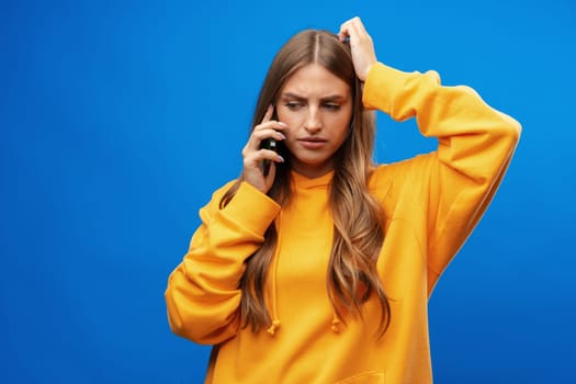 Portrait of young beautiful woman on the phone against blue background in studio
