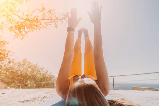 Fitness woman sea. Outdoor workout on yoga mat in park near to ocean beach. Female fitness pilates yoga routine concept. Healthy lifestyle. Happy fit woman exercising with rubber band in park.