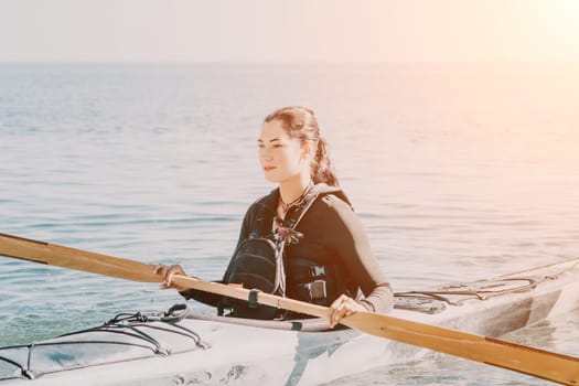 Happy smiling woman in kayak on ocean, paddling with wooden oar. Calm sea water and horizon in background