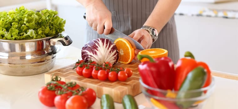 Chef Chop Juicy Orange Fruit Kitchen Photography. Vegan Cut Citrus with Knife in Hands. Healthy Vegetable Ingredient for Salad. Fresh Tomatoes, Cabbage and Pepper in Bowl. Culinary Blog Closeup Shot