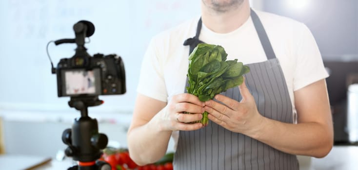 Kitchen Vlogger Holding Green Sorrel Leaf Bundle. Chef Showing Greens Bunch on Camera. Man Recording Healthy Culinary Recipe Vlog. Male Hands Holding Herbal Salad Ingredient. Horizontal Image