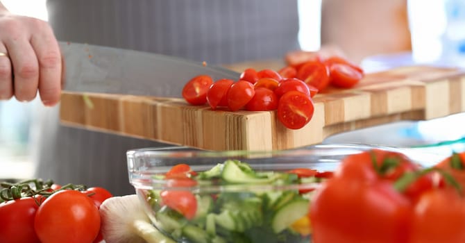 Chef Hands Pouring Cherry Tomato Cucumber Salad. Fresh Vegetable Dish in Glass Bowl. Male Cutting Red Ingredient into Small Slices. Healthy Home Culinary. Dieting Dish Horizontal Photography