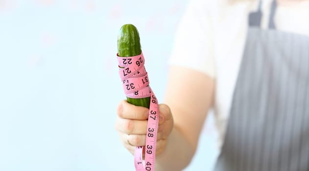 Chef Holding Centimeter Wrapped Ripe Cucumber. Culinary Man Measure Green Cuke Coiled in Centimetre. Man in Apron Standing with Ingredient in Hand. Vegetable Measurement Horizontal Photography