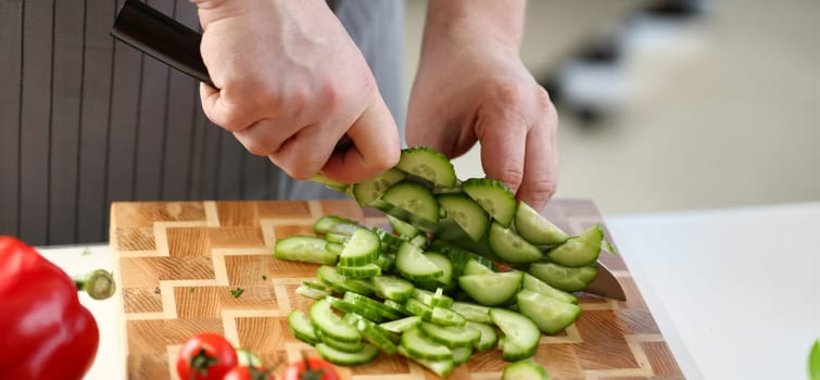 Culinary Male Chopping Green Dieting Cucumber. Chef Cutting Fresh Organic Cuke on Wooden Board at Kitchen. Sharp Knife Cut Ingredient to Small Slices. Healthy Food Concept Horizontal Photography
