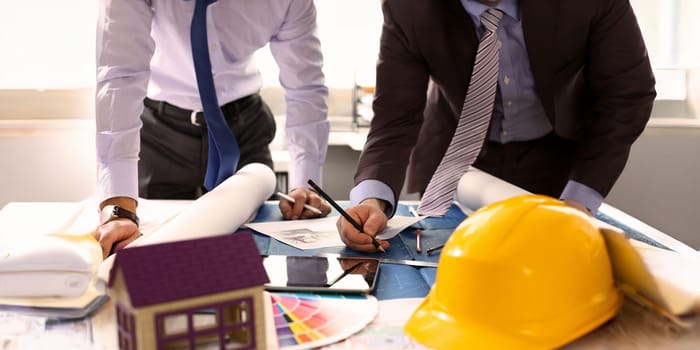 Engineer or Architectural Project Partnership. Building Design Concept. Engineering Hand Holding Pencil Making House Sketch on Blueprint. Yellow Helmet Architect Equipment at Workplace