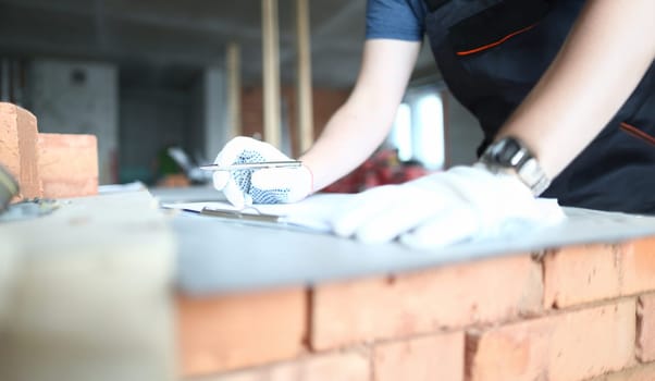 Male builder holds clipboard on background of an apartment under repair closeup. Estimated property value concept.