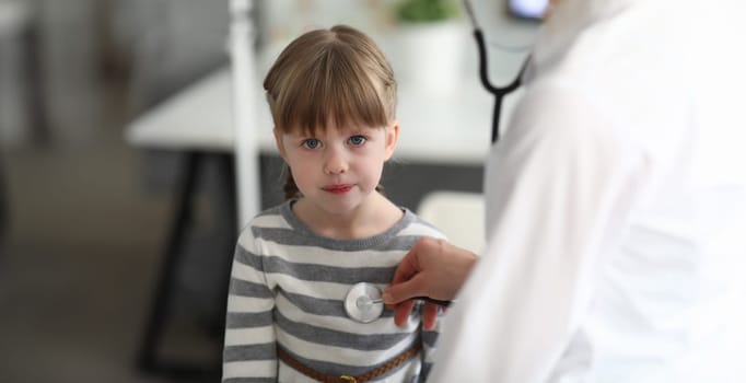 Portrait of smart female sitting in modern clinic office and looking at camera with joy. Professional physician measuring heartbeat with special utility. Health checkup concept