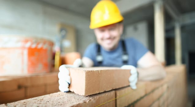 Male smiling builder puts make brickwork repair closeup. Sale of building materials concept.