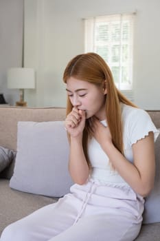 Asian woman coughing at home. Concept of health, illness, and discomfort.