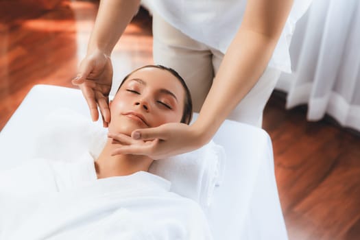 Caucasian woman enjoying relaxing anti-stress head massage and pampering facial beauty skin recreation leisure in dayspa modern light ambient at luxury resort or hotel spa salon. Quiescent