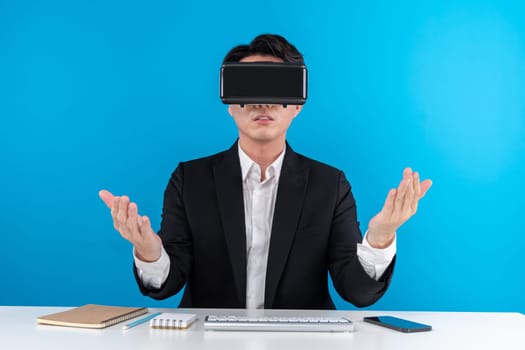 Asian businessman looking thorough VR connecting metaverse meeting in business world news futuristic metaverse, analyzing innovation technology in virtual reality isolated blue copyspace. Contrivance.