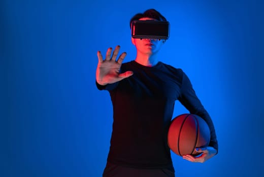 Asian athlete with VR holding a basketball player exploring virtual space on neon portrait sports training connecting digital futuristic hologram technology metaverse world playing court. Contrivance.