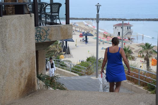 June 20, 2023 Netanya Israel, a woman goes down the stairs to the beach and sea. High quality photo