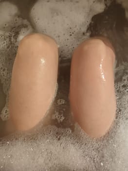 woman's feet in soapy bath water, cleanliness hygiene human health. High quality photo