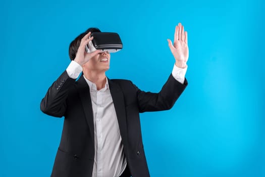 Asian businessman looking thorough VR while touching screen with connecting business world report in futuristic metaverse analyzing innovation technology virtual reality blue copyspace. Contrivance.