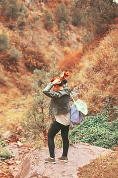 Female hiker walking in mountains forest. A woman tourist with a backpack is walking along a path in the woods in the mountains.
