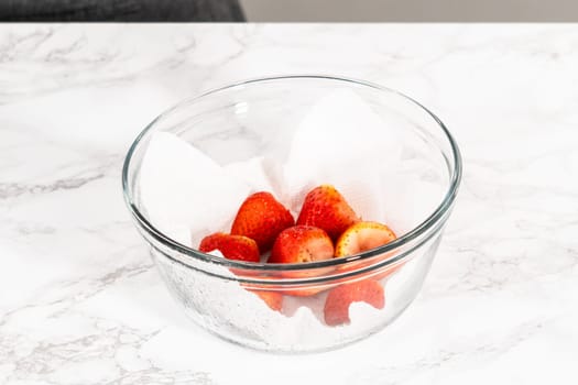 Freshly washed and dried strawberries are carefully arranged in a glass bowl lined with paper towel, ready for snacking or further use.