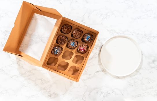 Flat lay. Preparing to share the delicious chocolate cupcakes, the final step involves carefully packaging them into a brown paper cupcake box.