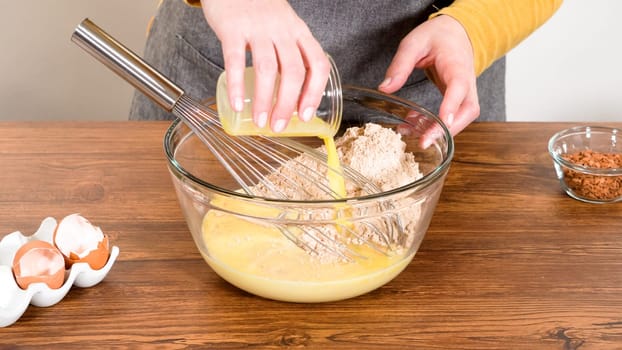 In a glass mixing bowl, a large hand whisk expertly blends the ingredients for a delectable gingerbread bundt cake with caramel frosting.