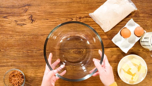 Flat lay. In a glass mixing bowl, a large hand whisk expertly blends the ingredients for a delectable gingerbread bundt cake with caramel frosting.