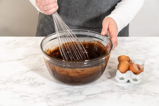 In the process of creating mouthwatering chocolate cupcakes, the first step involves meticulously mixing the ingredients in a glass mixing bowl to make the perfect batter.