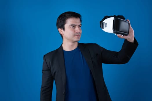 Profile smiling businessman holding VR headset looking metaverse posing portrait isolated blue background futuristic technology in virtual reality in meta finance business digital data. Contrivance.