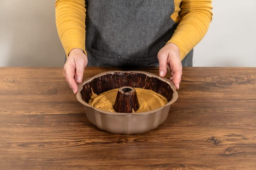 Pouring the gingerbread cake batter into the greased bundt cake pan, ready for a delightful caramel frosting.