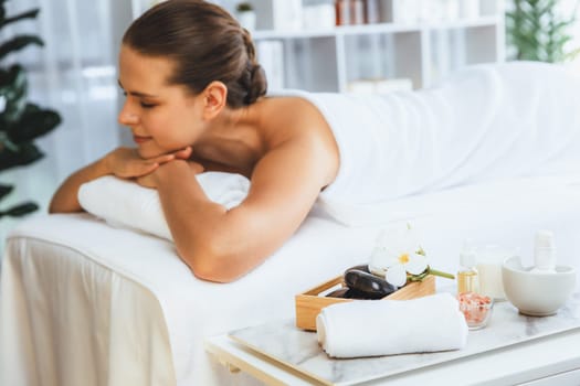 Aromatherapy massage on daylight ambiance or spa salon composition setup with focus decor and spa accessories on blur woman enjoying blissful aroma spa massage in resort or hotel background. Quiescent