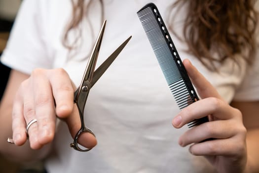 Scissors and comb in the hands of female barber