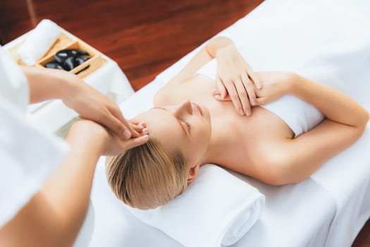 Caucasian woman enjoying relaxing anti-stress head massage and pampering facial beauty skin recreation leisure in dayspa modern light ambient at luxury resort or hotel spa salon. Quiescent