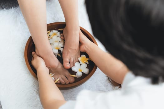 Woman indulges in blissful foot massage at luxurious spa salon while masseur give reflexology therapy in gentle day light ambiance resort or hotel foot spa. Quiescent