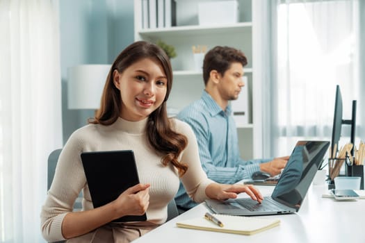 Smiling beautiful woman working on laptop aligning taking note to pose for looking at camera photo shooting portrait profile's business with smart coworker at modern office at morning time. Postulate.