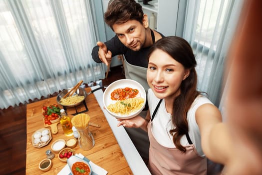 Making photo selfie in couple chef influencers completely cooked spaghetti with meat topped with tomato sauce special dish recording on camera, serving healthy food at modern home chanel. Postulate.