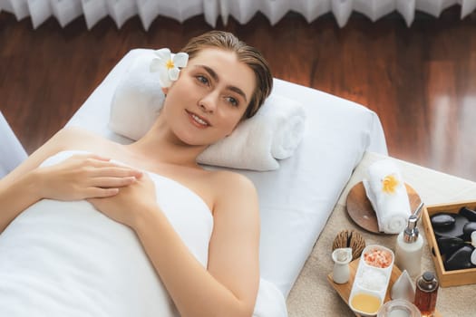 Caucasian woman customer enjoying relaxing anti-stress spa massage and pampering with beauty skin recreation leisure in day light ambient salon spa at luxury resort or hotel. Quiescent