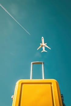 Adventure awaits yellow suitcase underneath jet plane flying in blue sky travel concept photo