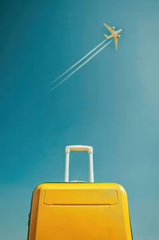 Idyllic beach travel scene with yellow suitcase, airplane flying overhead, relaxing vacation atmosphere