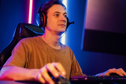 Host channel of gaming smart streamer playing online game to be winner, wearing headphone with viewers live steaming on media social online for selected team competition at neon light room. Pecuniary.