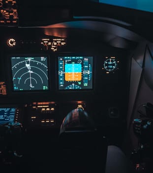 Cockpit view of an airplane during a night-time flight with illuminated instrument panels