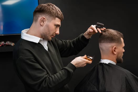 Young barber expertly trims a man's hair with a trimmer in the barbershop