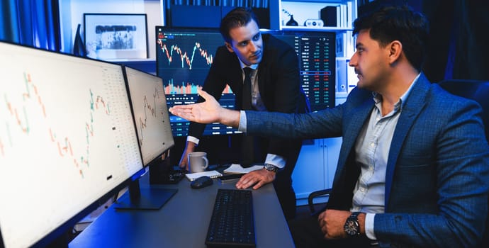 Two stock investors discussing and pointing interesting market stock on monitor. Trend of the technology for dynamic economic investment for planning to select at neon light workplace. Sellable.