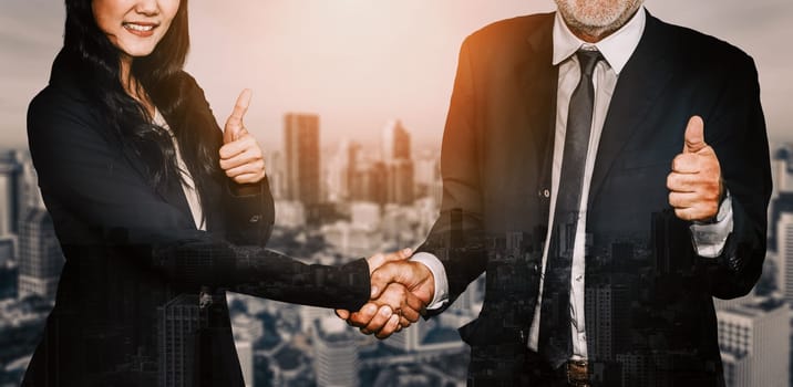 Double exposure image of business people handshake on city office building in background show partnership success of business deal. Concept of corporate teamwork, trust partner and work agreement. uds