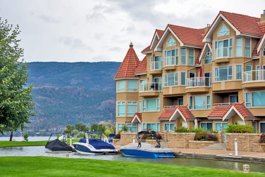 Luxury residential area with motor boats piered on water channel in front and green lawn.